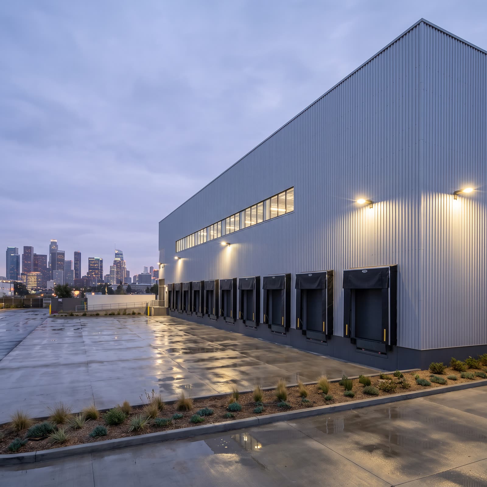 A distribution warehouse with loading docks, the downtown Los Angeles skyline behind it